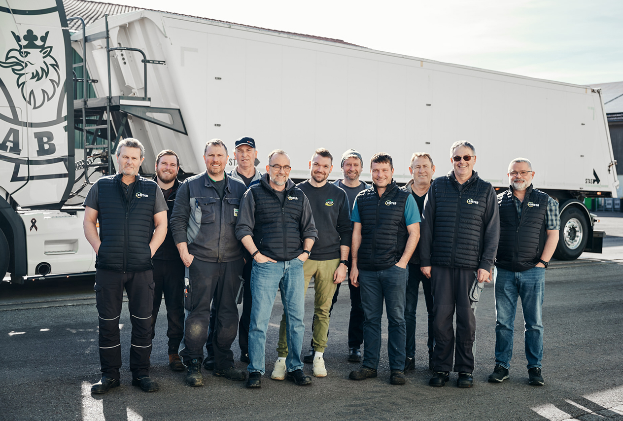 Teamfoto der Abteilung Logistik vor einem Lkw in Arbeitskleidung und Westen von Emter