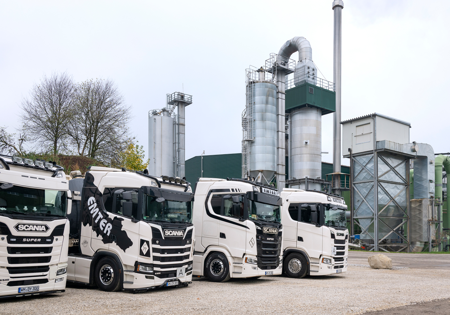 Moderne schwarz weiß bedruckte LKWs parken vor der industriellen Anlage von Emter