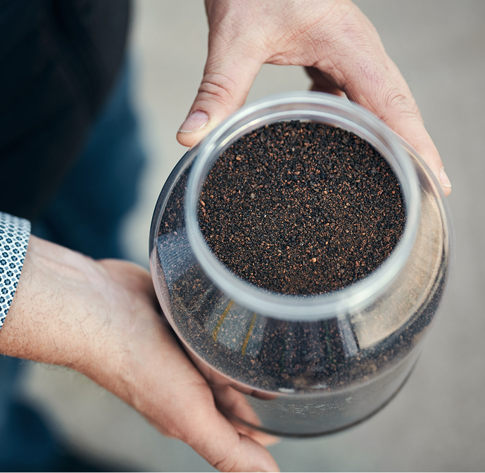 Eine Detailaufnahme von einem Glas gefüllt mit Phosphor, das von einer Person gehalten wird.